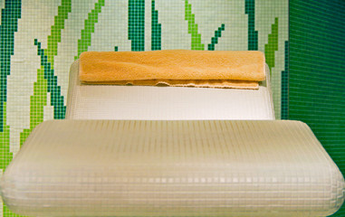 Closeup or detail view of heated mosaic tiled lounger inside thermal suite in wellness or spa area...