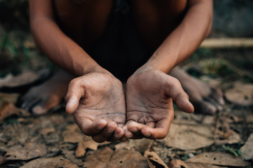 hands poor child or beggar begging you for help sitting at dirty slum. concept for poverty or hunger people,human rights,donate and charity for underprivileged children in third world 