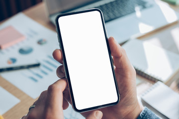 Mockup image blank white screen cell phone.man hand holding texting using mobile on desk at home office.background empty space for advertise text.people contact marketing business,technology 