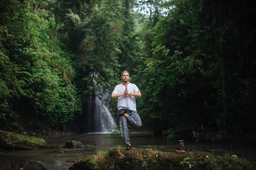 Yoga practice and meditation in nature. Man practicing near river