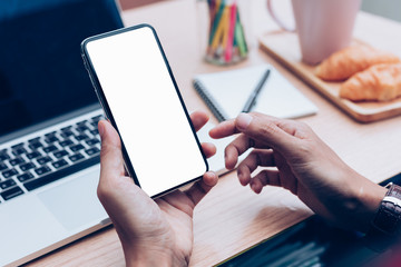 Mockup image blank white screen cell phone.man hand holding texting using mobile on desk at home office.background empty space for advertise text.people contact marketing business,technology 