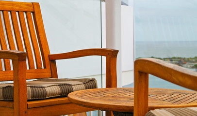 Detail or close up of comfortable wooden deck chairs with table and striped upholstery on outside...