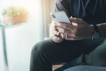 using cell phone.hand holding texting message on screen mobile chatting friend ,search internet information sitting on sofa in office.technology device contact communication connecting people concept