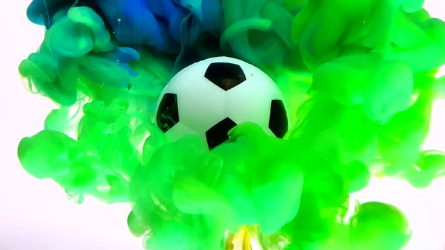 Soccer ball on a beautiful blue-green background. Concept of advertising football competition. Colored ink in water. Fantastic amazing screensaver.