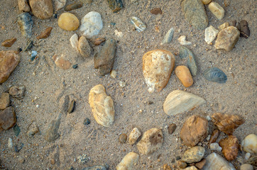 Fototapeta na wymiar Pebbles on the river beach. Natural background of pebbles and sand by the river.