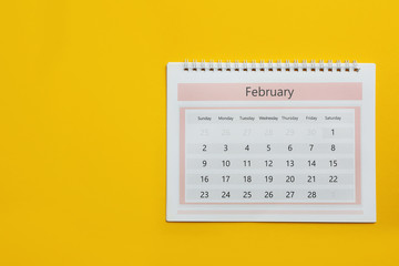 February calendar on yellow background, top view. Space for text