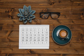 Flat lay composition with calendar and cup of coffee on wooden table