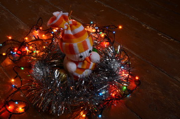 toy snowman among garlands on a wooden floor