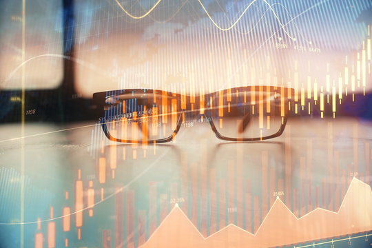 Financial graph hologram with glasses on the table background. Concept of business. Double exposure.