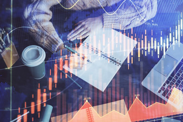 Forex graph on hand taking notes background. Concept of research. Double exposure