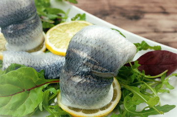 Pickled herring with mixed salad on wooden table.