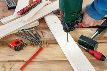 Drill work. Making hole into the wood with drill bit.
