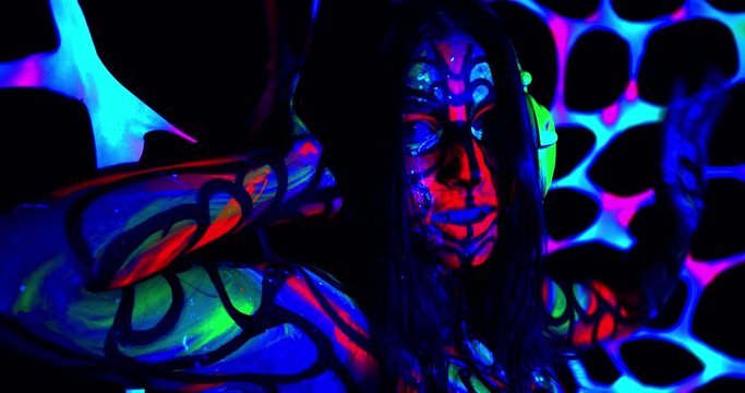 Young woman with glowing makeup and body art at the party, posing, 4k