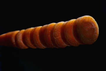 sliced carrots in the air on a dark background