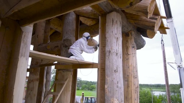 Building construction outdoors with professional equipment and machinery. Clip. Farm householding with a man polishing a wooden log with a grinding machine.