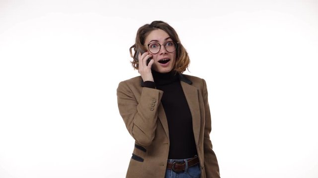 European stylish young woman receiving good news while talking on mobile phone isolated over white background and got super excited. Emotions concept