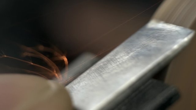 a carpenter grinds a chisel on a grinder. macro 4k