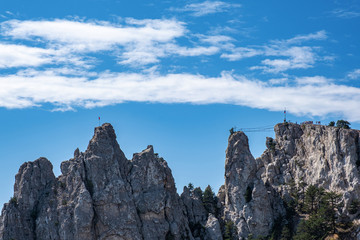 Fototapeta na wymiar Sharp Ai-Petri cliffs with suspension bridge against a blue sky.