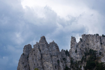 Fototapeta na wymiar The sharp cliffs of Ai-Petri with a suspension bridge against a cloudy sky.