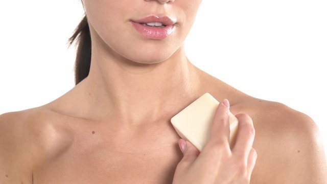 Slim naked woman is gently touching her decollate with a bar of soap. Skincare concept