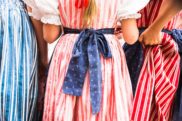 Rear view closeup of three standing school girls dancers, one fixing her South Bohemian period folklore dress. Costumes local to Cesky Krumlov area - UNESCO heritage site, Czech Republic.