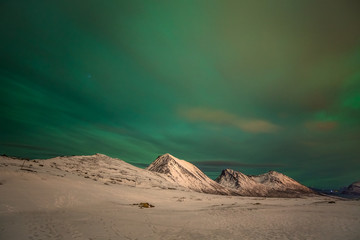 Dramatic polar lights, Aurora borealis with many clouds and stars on the sky over the mountains in the North of Europe - Tromso, Norway.long shutter speed.