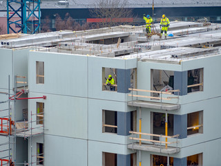 Builders with crane building multistorey house. Winter or autumn background. Builders Workers with crane on a apartment house. Under blue sky. business concept