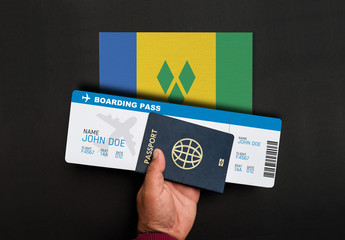 Hand holds passport and boarding pass with flag of Saint Vincent and the Grenadines