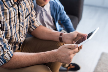 cropped view of jewish father and son using digital tablet in apartment