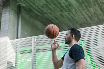 Attractive basketball player plays spinning his ball on a finger of his right hand while walking