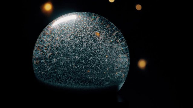 Christmas snow globe animation on hand. A garland of lights glows in the background.