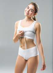 Fototapeta premium Close up of young woman measuring her bust size with tape measure isolated on white background