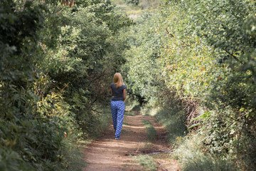 rear view of blonde woman walking on forest path