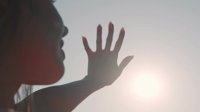 girl looks at the sun through her hand. portrait of a young woman in the sun