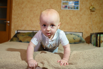 Fototapeta premium A small child plays on the bed at the parents. Happy childhood.