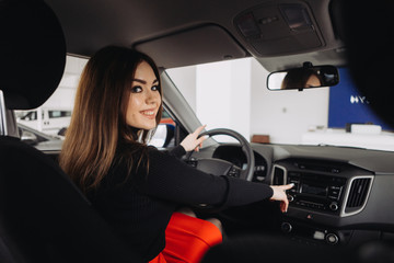 A young businesswoman is choosing a new car in a car store