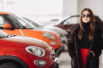 A young businesswoman is testing cars in a car store