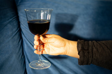 Hand catching a glass of red wine under sunlight.
