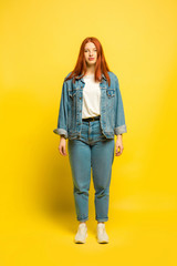 It's easy to be follower. Minimal and comfort style in clothes. Caucasian woman's portrait on yellow background. Beautiful red hair female model. Concept of human emotions, facial expression, sales