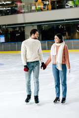 Fototapeta premium beautiful smiling couple holding hands on skating rink