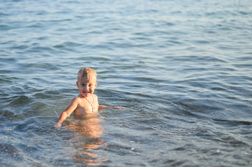 three year old little boy having fun at summer vacation in sea with his family