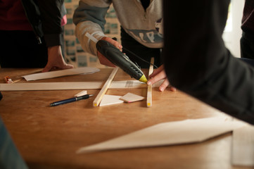 A person gluing on a wooden strut
