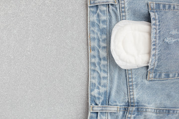 White feminine pad in the back pocket of jeans on silver gray background © velirina