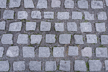 Top view of granite cobblestoned pavement background. Full frame of regular square cobbles in lines. Natural stone textured background