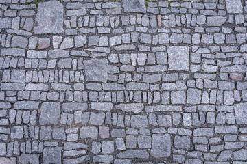 Top view of granite cobblestoned pavement background. Full frame of irregular small and big cobbles in lines. Natural stone textured background