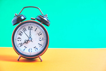 Vintage old alarm clock on a background of pastel retro colors.