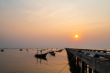Fototapeta na wymiar Beautiful seascape sunset with silhouette fishing wood boat floating down on sea at jetty in asia