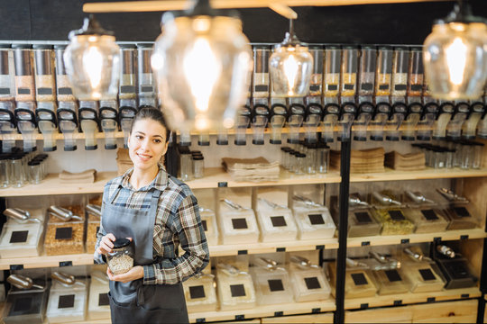 Portrait Of Beautiful Young Woman Standing At A Juice Bar Counter And Looking Away Smiling. Successful Female Juice Bar Owner.