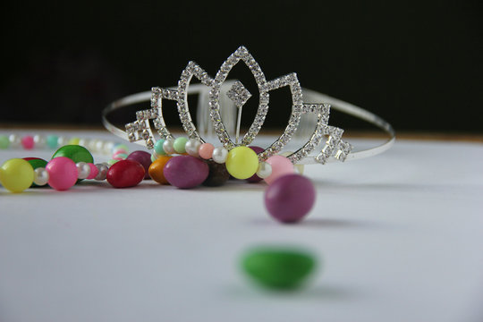 silver tiara next to children's multicolored beads and sweets in multi-colored glaze