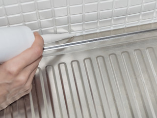 Using silicone adhesive to installing a sink in the kitchen. Professional repair man service...